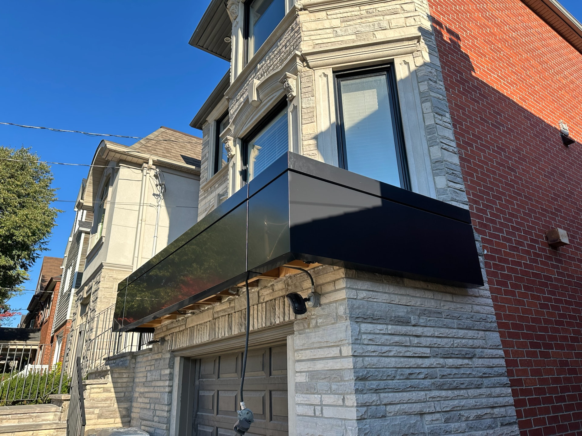 Home exterior with a black ACM panel canopy built over the garage