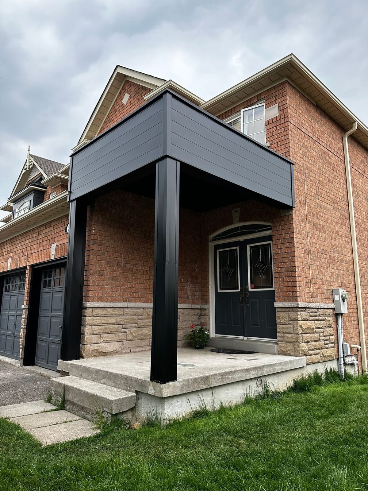 Entrance posts and canopy wrapped in black aluminum by Ribonga